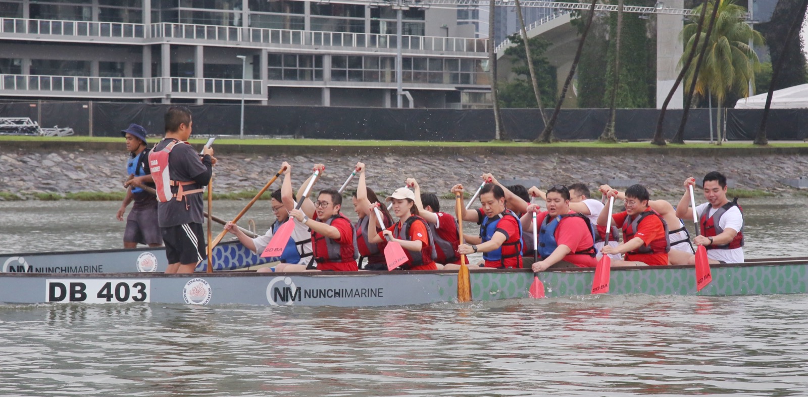 Young PAP and NTUC Youth members paddling together at a dragonboat team-building event in Singapore